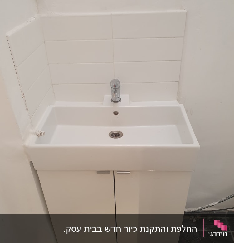 כיור לבן עם ברז כרום מותקן על ארון